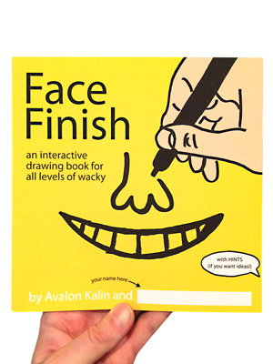 image of a hand holding a book. the cover has a an image of a hand drawing a nose and mouth. the book is title Face Finish